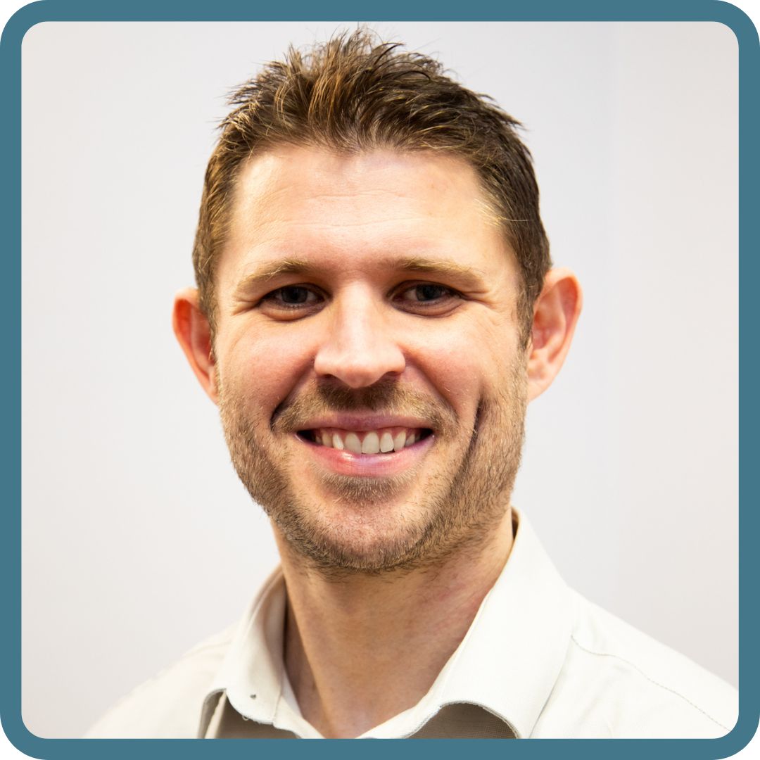 Man smiles at camera with white shirt and brown hair